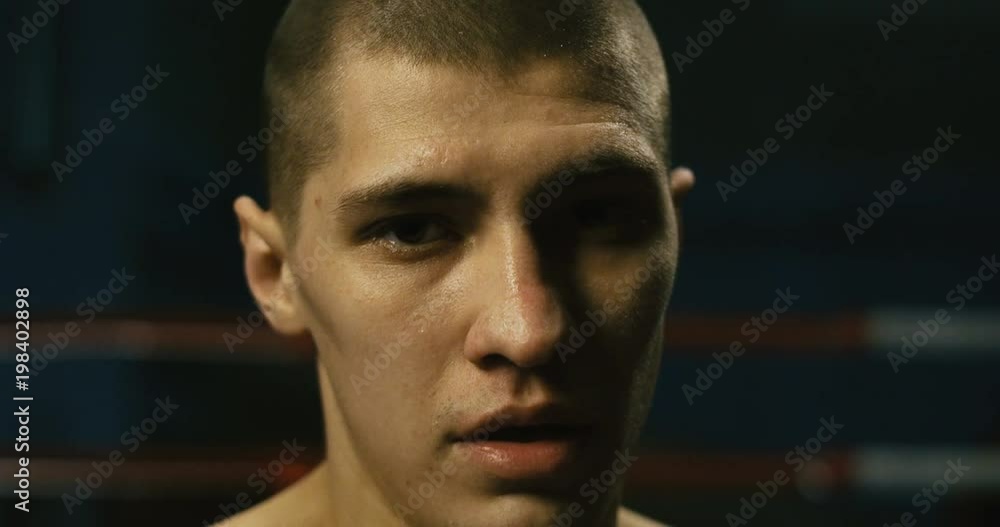 Young serious man standing shirtless on boxing ring and looking focused at the camera. Young serious man standing shirtless on boxing ring and looking focused at the camera.