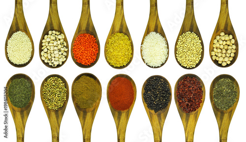 Various colorful legumes, cereals and spices in wooden spoons.