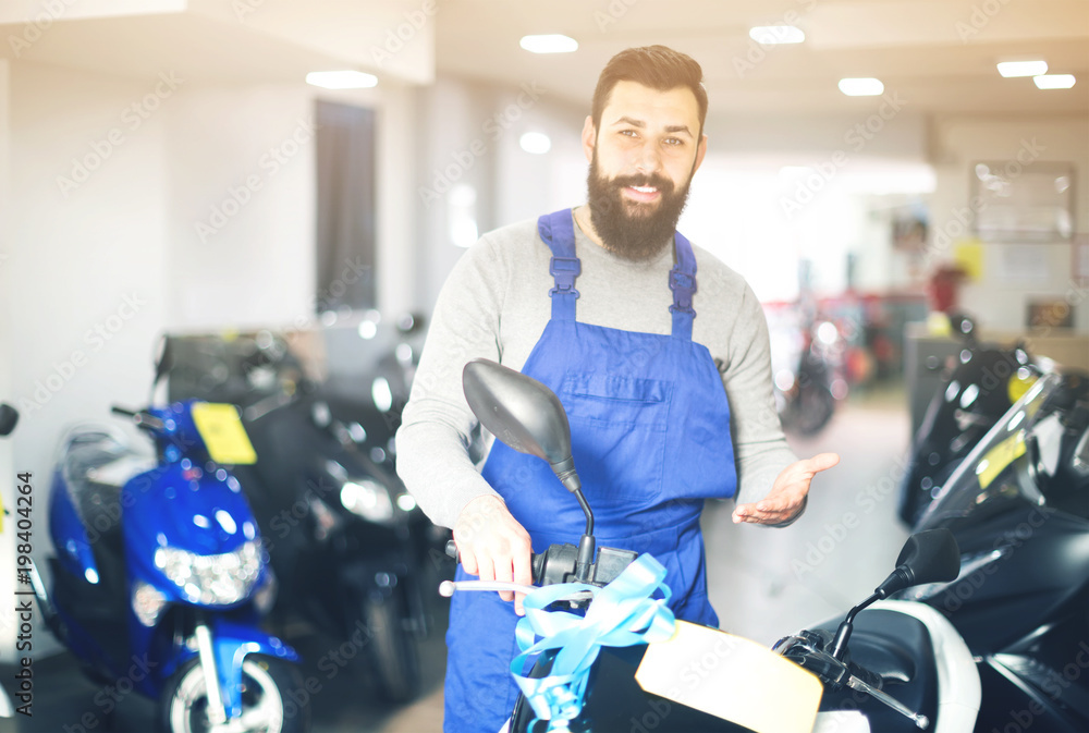 © JackF - friendly man worker displaying various motorcycles in workshop