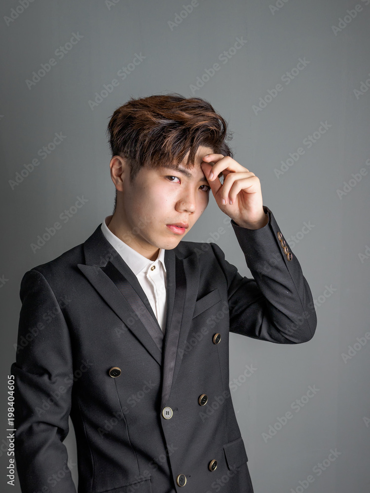 Portrait of a smart young Chinese man standing against gray background, looking at camera with confidence expression. Portrait of a smart young Chinese man standing against gray background, looking at camera with confidence expression.