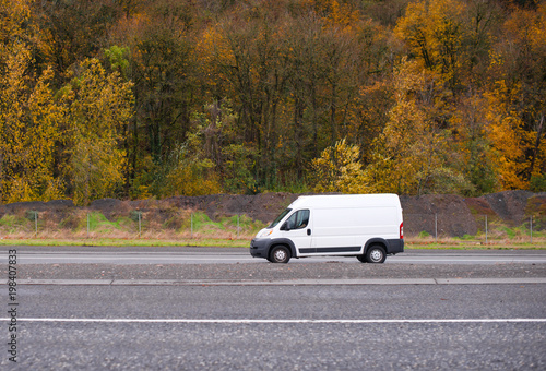 Commercial cargo and small business mini van going on the road with autumn yellow trees on the background