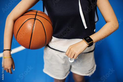 Teenage girl holding a basketball on the court