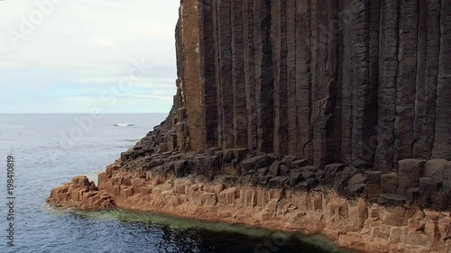 Close-up of vertical basalt columns of Fingal's Cave on Staffa Island, west of Isle of Mull in Scotland. Calm waves touching the rocks. Steady shot in high frame rate. photo