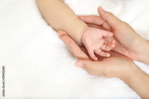 小さな赤ちゃんの手を母が両手で包むイメージ