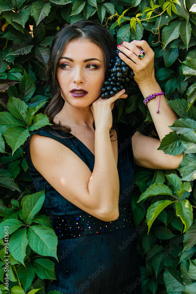 Portrait of young sexy brunette with black grapes. Portrait of young sexy brunette with black grapes.