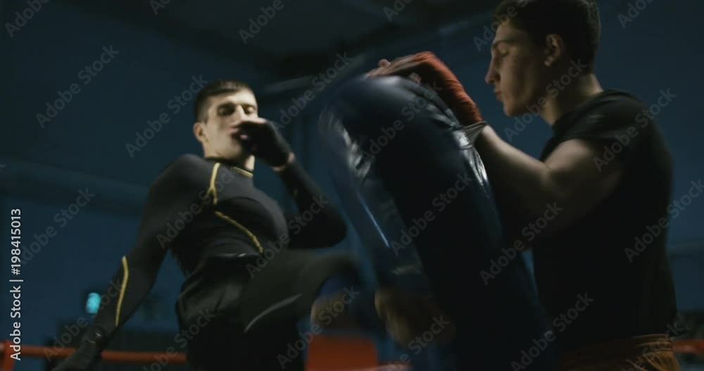 Coach holding boxing bag and training sportive man to attack and learn technique of Thai box. Coach holding boxing bag and training sportive man to attack and learn technique of Thai box.