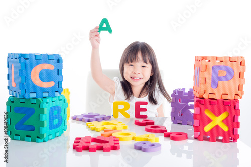 Little asian girl playing alphabet toy over white background