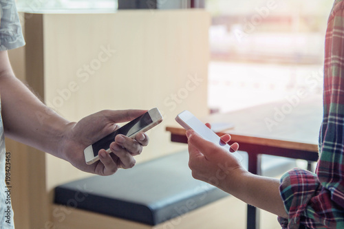 Close up of men and woman hands holding touching mobile phone with blank copy space for your text message in cafe with light Sunset,Vintage tone.Selective focus