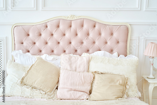 Photos Large buttoned headboard of luxury bed, beige and pink pillows on it, copy space