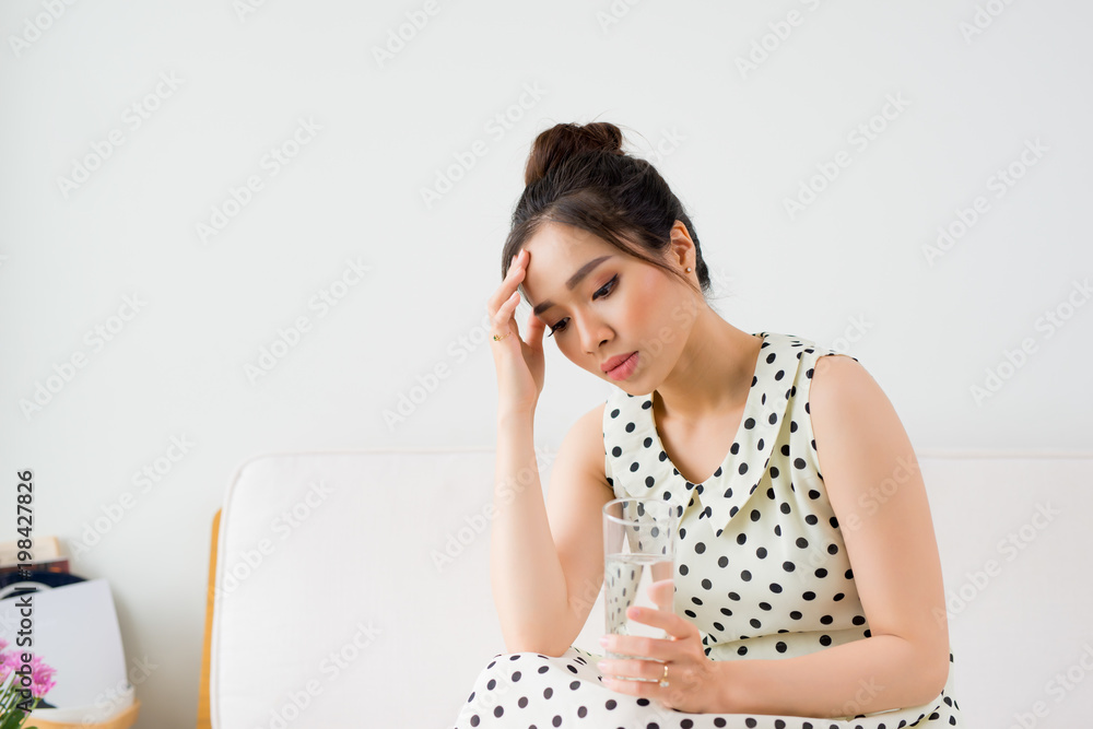 Upset Vietnamese woman on couch at home in the living room Upset Vietnamese woman on couch at home in the living room