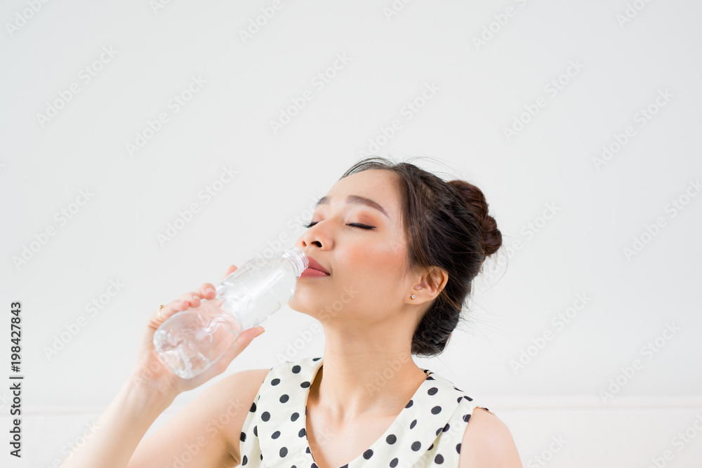 Young beautiful asian woman holding a glass of water while sitting at home Young beautiful asian woman holding a glass of water while sitting at home