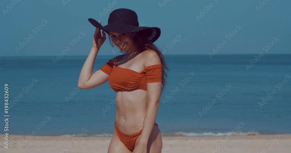 Beautiful girl in bikini and hat relaxing in the sun during summer holiday on the tropical beach - video in slow motion Beautiful girl in bikini and hat relaxing in the sun during summer holiday on the tropical beach - video in slow motion