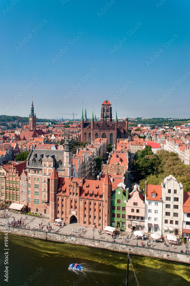 Gdansk Old City in Poland with Gothic St Mary church, Mariacka Gate, City Hall tower, historical houses and the promenade along the riverbank of Motlawa river. Aerial view. Vertical.