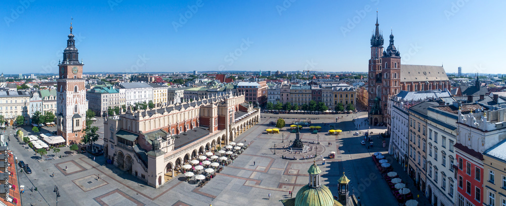 Wide panorama of Krakow old city in Poland with Main Market Square (Rynek), old cloth hall (Sukiennice), town hall tower, St. Mary church (Mariacki) and renovated Mickiewicz statue.  Aerial view