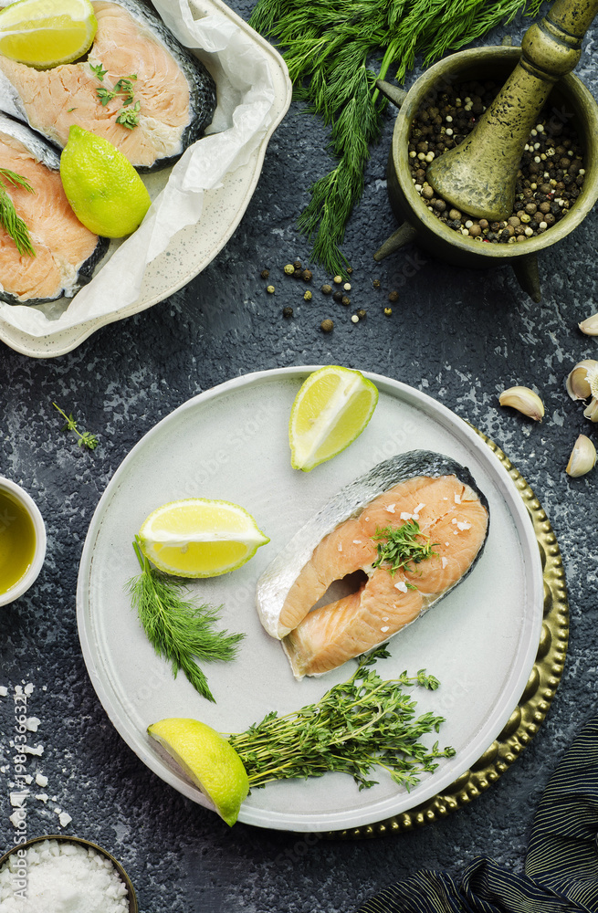 Fresh raw salmon steak placed with lemon,garlic,salt and mixed pepper,olive oil,organic oregano and dill.Top view with close-up Fresh raw salmon steak placed with lemon,garlic,salt and mixed pepper,olive oil,organic oregano and dill.Top view with close-up