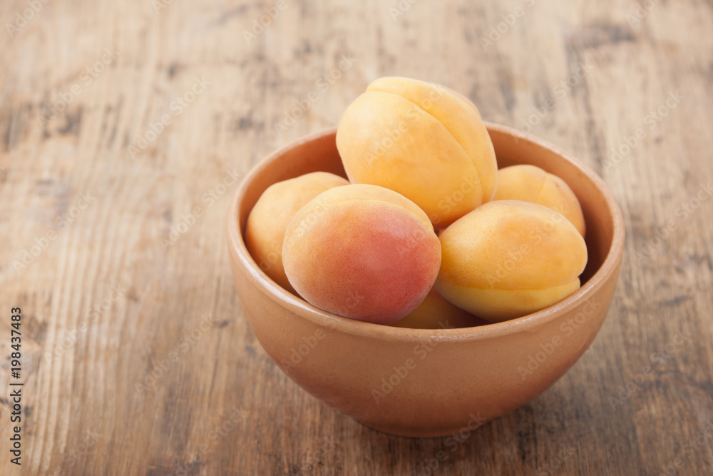 Apricots in a clay bowl on a wooden table Apricots in a clay bowl on a wooden table