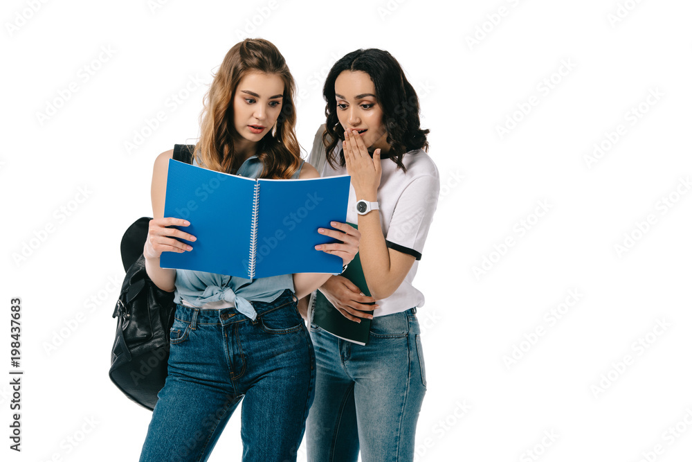 surprised multicultural students looking at copybook isolated on white surprised multicultural students looking at copybook isolated on white