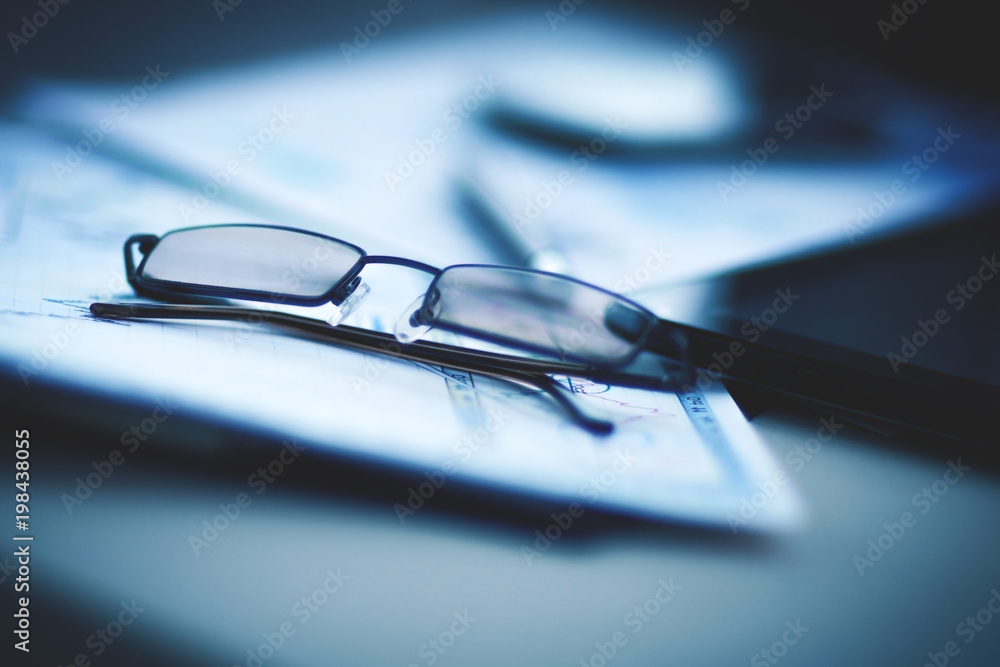 Eyeglasses lie on the documents and charts, next to the Tablet PC Eyeglasses lie on the documents and charts, next to the Tablet PC