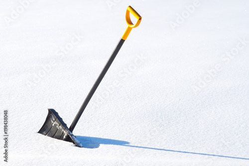Black and yellow snow shovel standing in a snow
