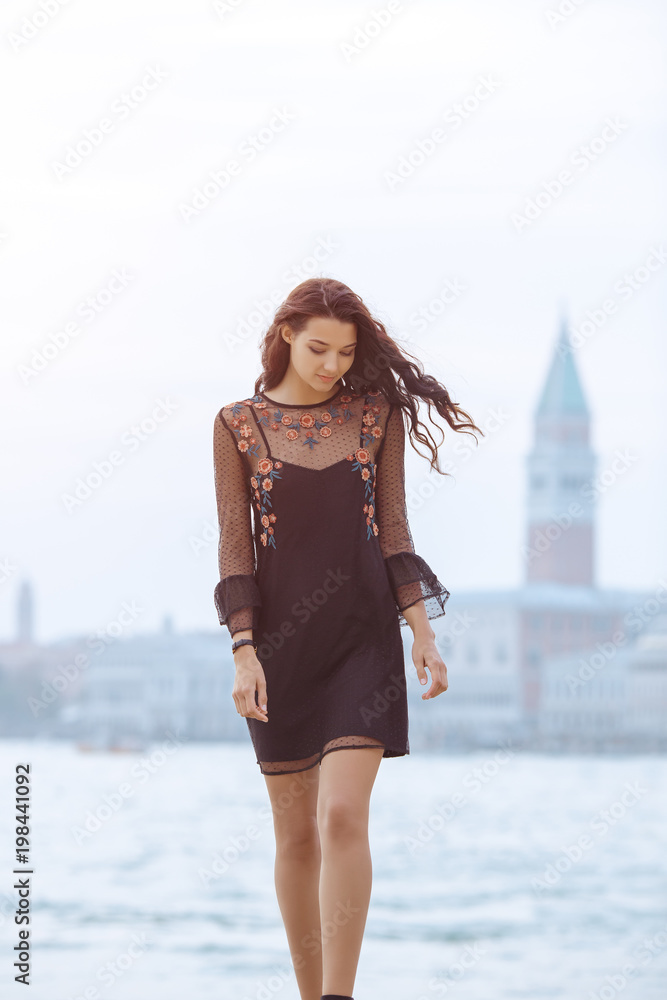 Fototapeta premium Podróżować turystyczną kobiety pozycję na molu przeciw pięknemu widokowi na weneckim chanal z łodziami w Wenecja, Włochy. Atrakcyjna młoda romantyczna dziewczyna na urlopowy chodzić szczęśliwy kanał grande. Wspaniały mieszany
