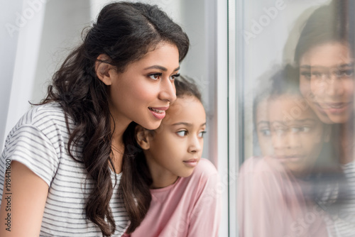 close-up shot of mother and daughter looking through window