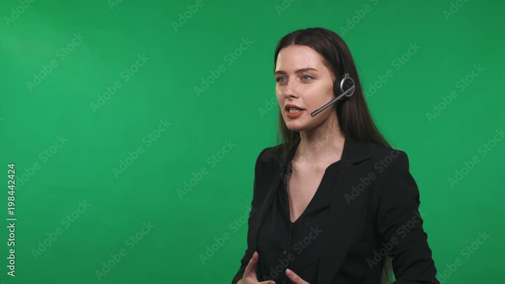 Girl call center operator in headphones answers the call, support, green background.
Girl call center operator in headphones answers the call, support, green background.