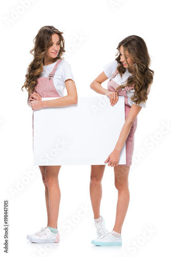 attractive young twins holding blank placard isolated on white