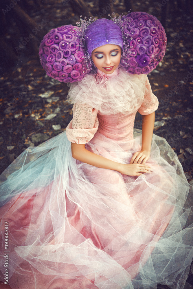 Beautiful model wearing pink dress is posing in a creative wig Beautiful model wearing pink dress is posing in a creative wig