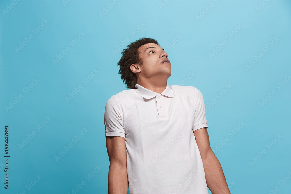Let me think. Doubtful pensive man with thoughtful expression making choice against blue background Let me think. Doubtful pensive man with thoughtful expression making choice against blue background