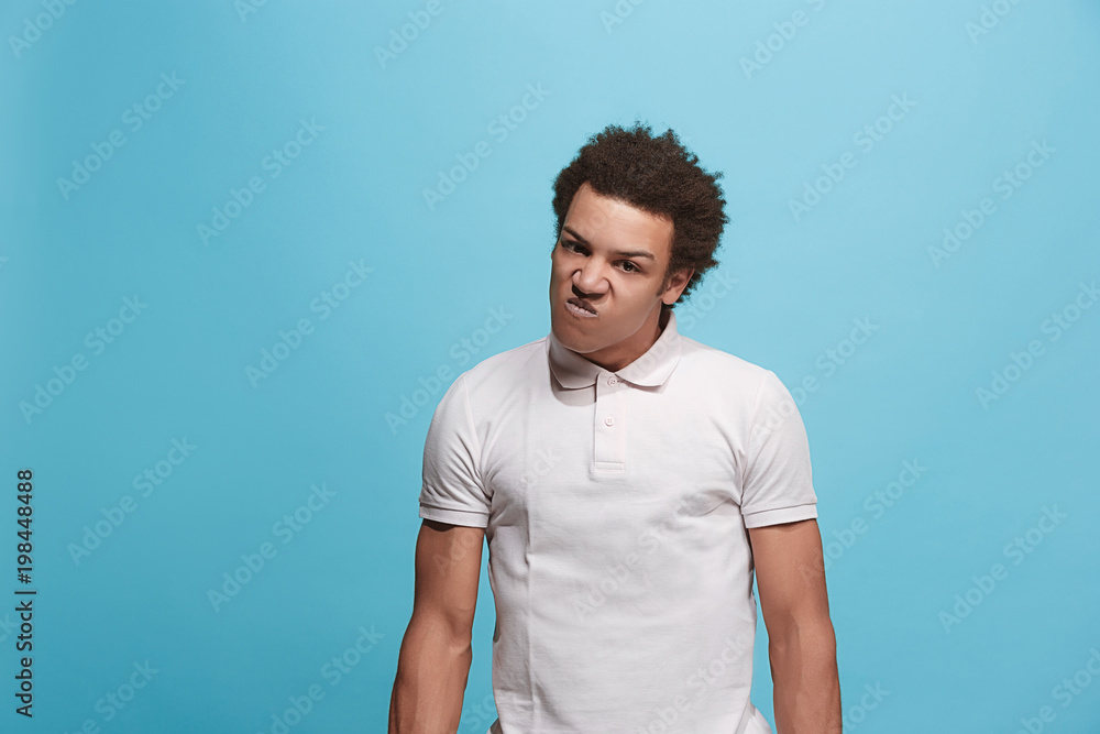 The young emotional angry man screaming on blue studio background The young emotional angry man screaming on blue studio background