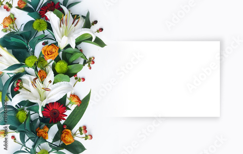 A beautiful floral arrangement with white lilies and an empty sheet of paper for congratulations. A bouquet of flowers on a white background with copy space.