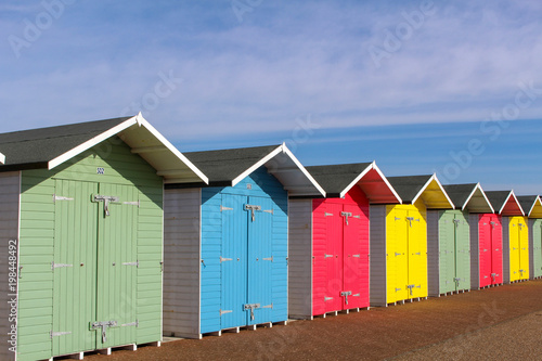 a row of colourful beach huts, against a blue sky