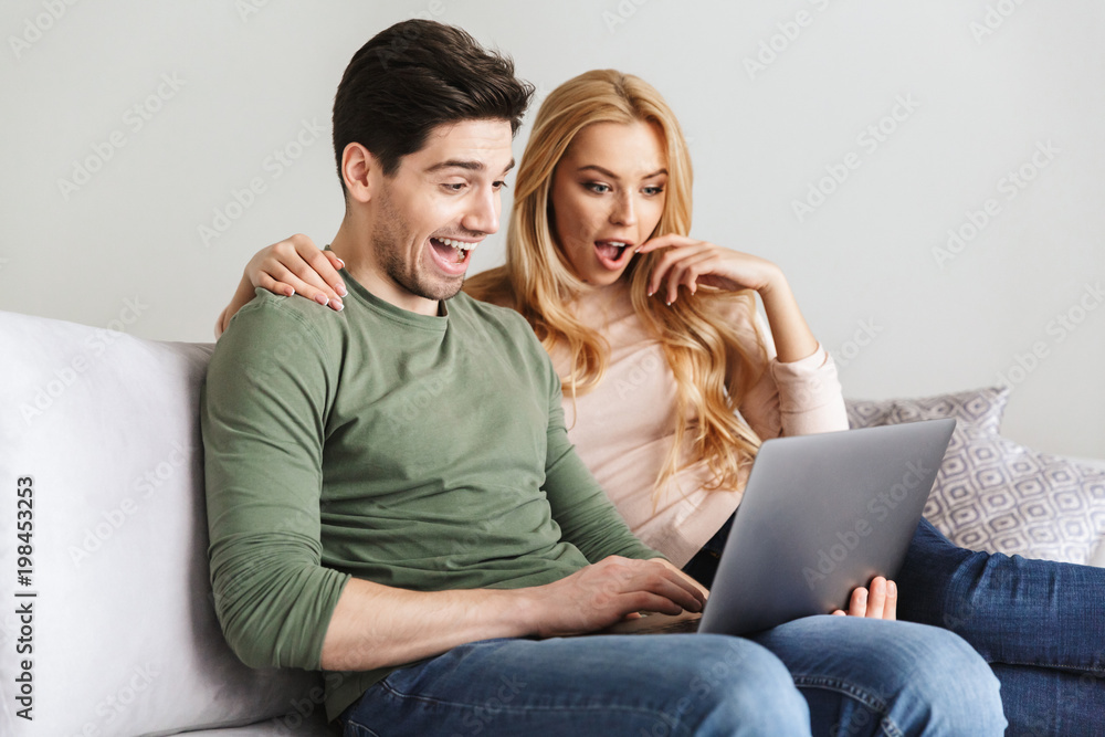 Excited surprised young loving couple using laptop computer. Excited surprised young loving couple using laptop computer.