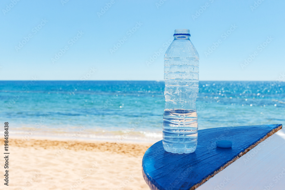 Closeup of the sea view and plastic bottle with water on table Closeup of the sea view and plastic bottle with water on table