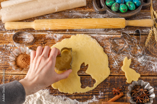 Dough for baking curly cookies and hand holding a mold. Still-life on a wooden background. photo