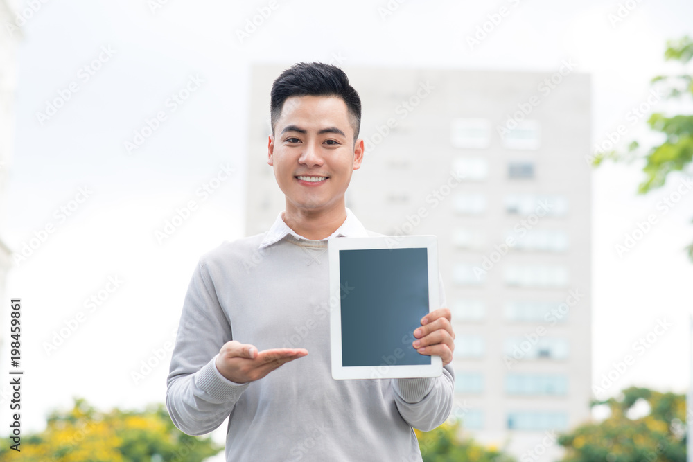 Young Businessman holding and showing the screen of digital tablet