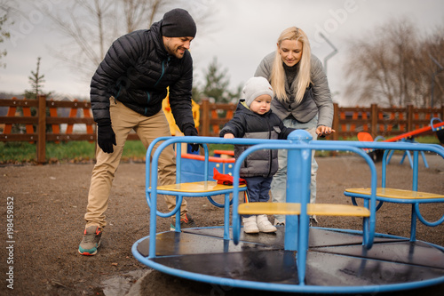 Smiling family couple with little son riding on the carousel