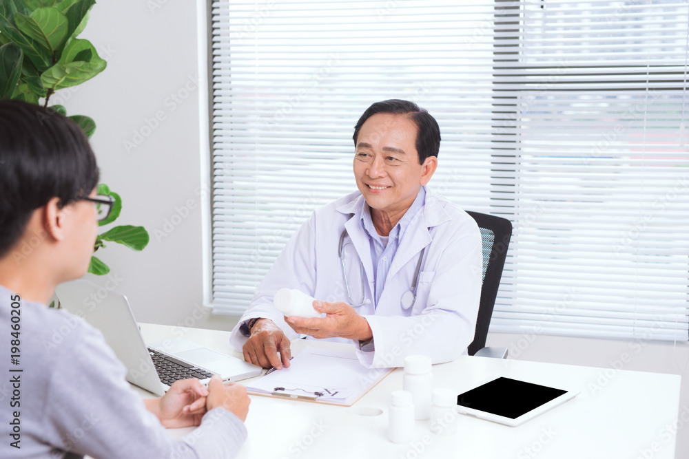 Portrait of senior doctor sitting at his desk in medical office Portrait of senior doctor sitting at his desk in medical office