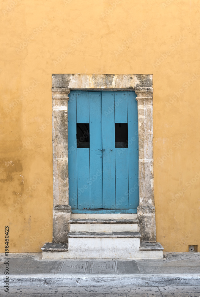 Yellow house with blue wooden door in San Francisco de Campeche, Mexico