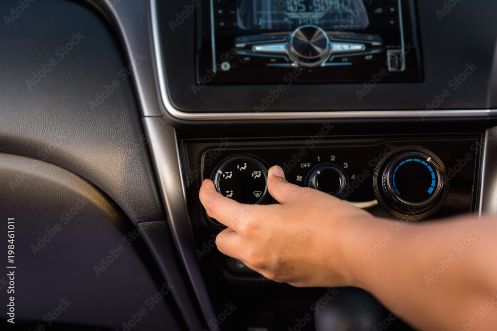 Close-up portrat of woman hand turning on/off car air conditioning system
