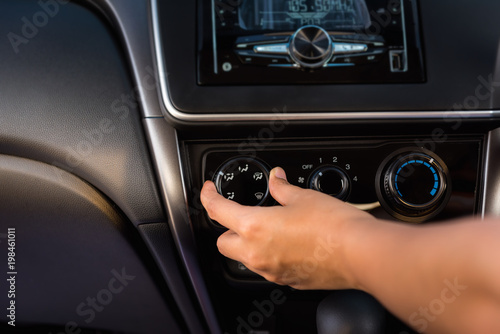 Close-up portrat of woman hand turning on/off car air conditioning system photo