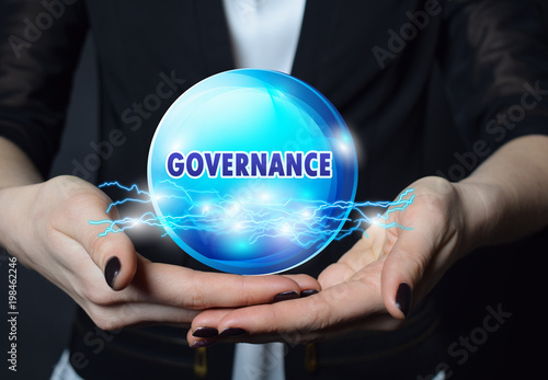 In the hands of a businessman, a neon circle with the inscription:GOVERNANCE