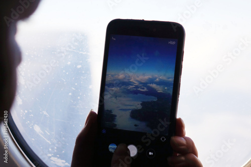 Woman taking pictures from the window of the plane.