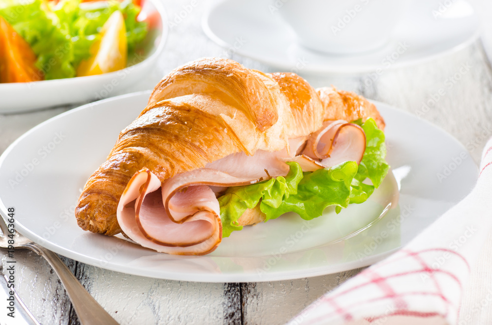 Fresh croissant with ham and salad leaf with sfresh salad on white wooden background Fresh croissant with ham and salad leaf with sfresh salad on white wooden background