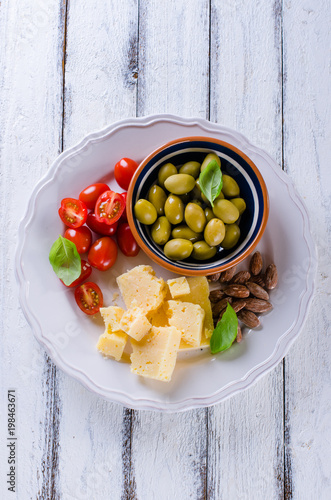 Antipasti plate of parmesan, cherry tomatoes, olives and almonds photo