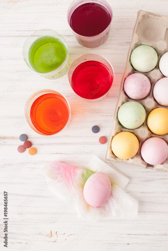 Colored eggs in a box and painted egg with a glass of diluted paint
