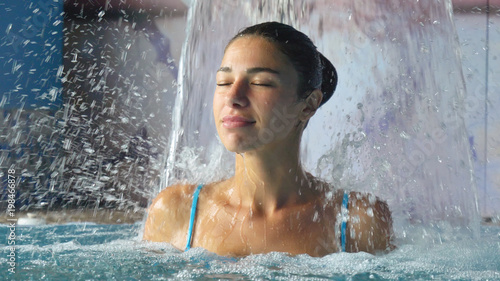 Beautiful young girl  woman  relaxed in a spa  in a blue bathing suit  on a blue background. Concept  spa procedures  body massages  spa cream  relax  spa water treatments  swimming pool