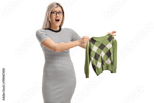 Shocked young woman holding a shrunken blouse and looking at the camera