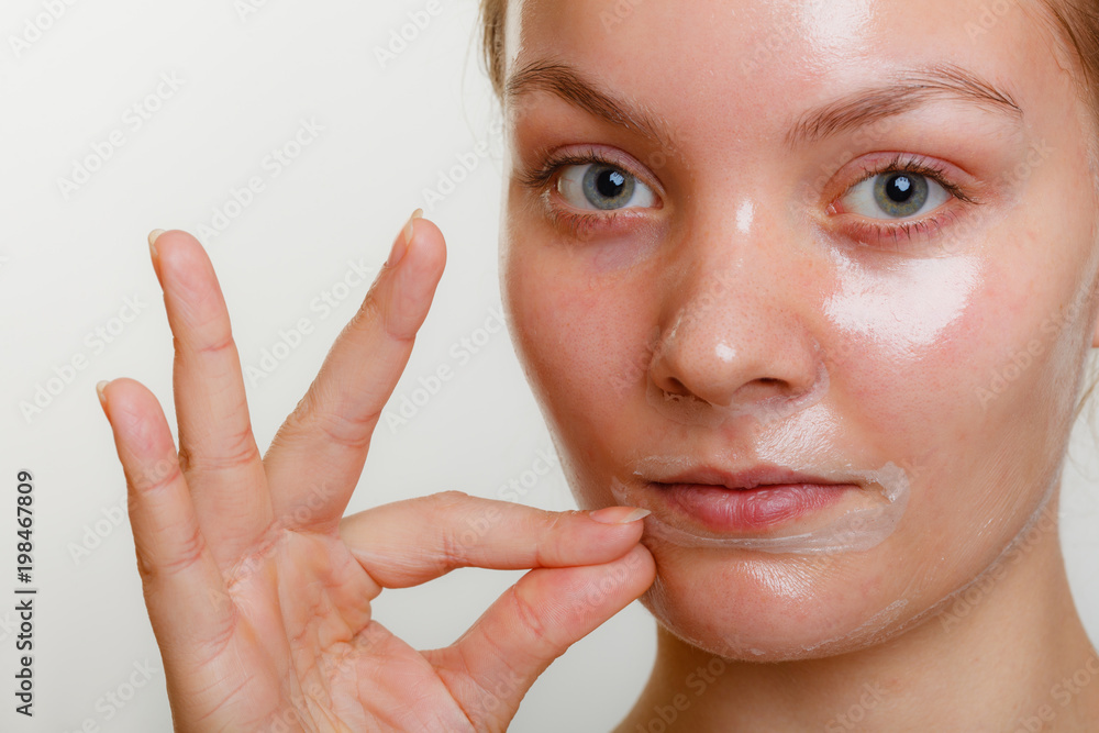 Woman removing facial peel off mask. Woman removing facial peel off mask.