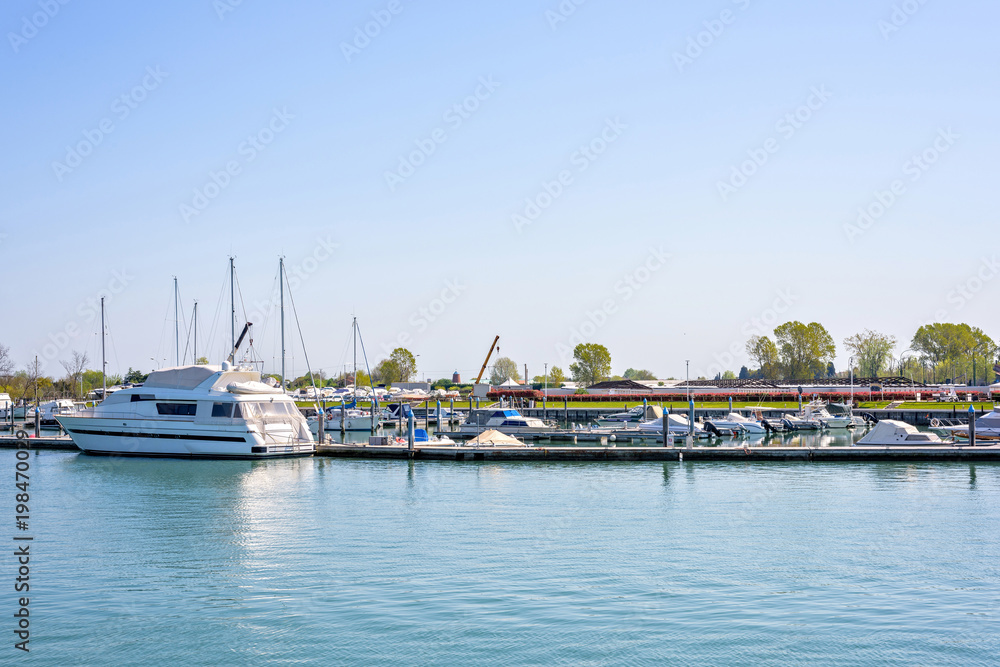 Daylight view to a port with parked yachts and trees
